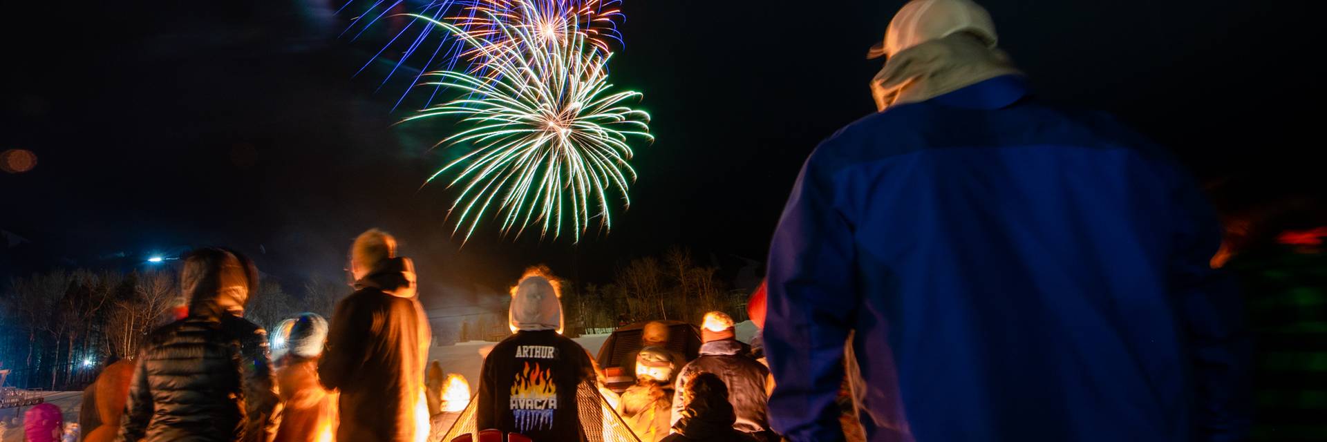 People standing and watching fireworks at Sunday River in the winter.