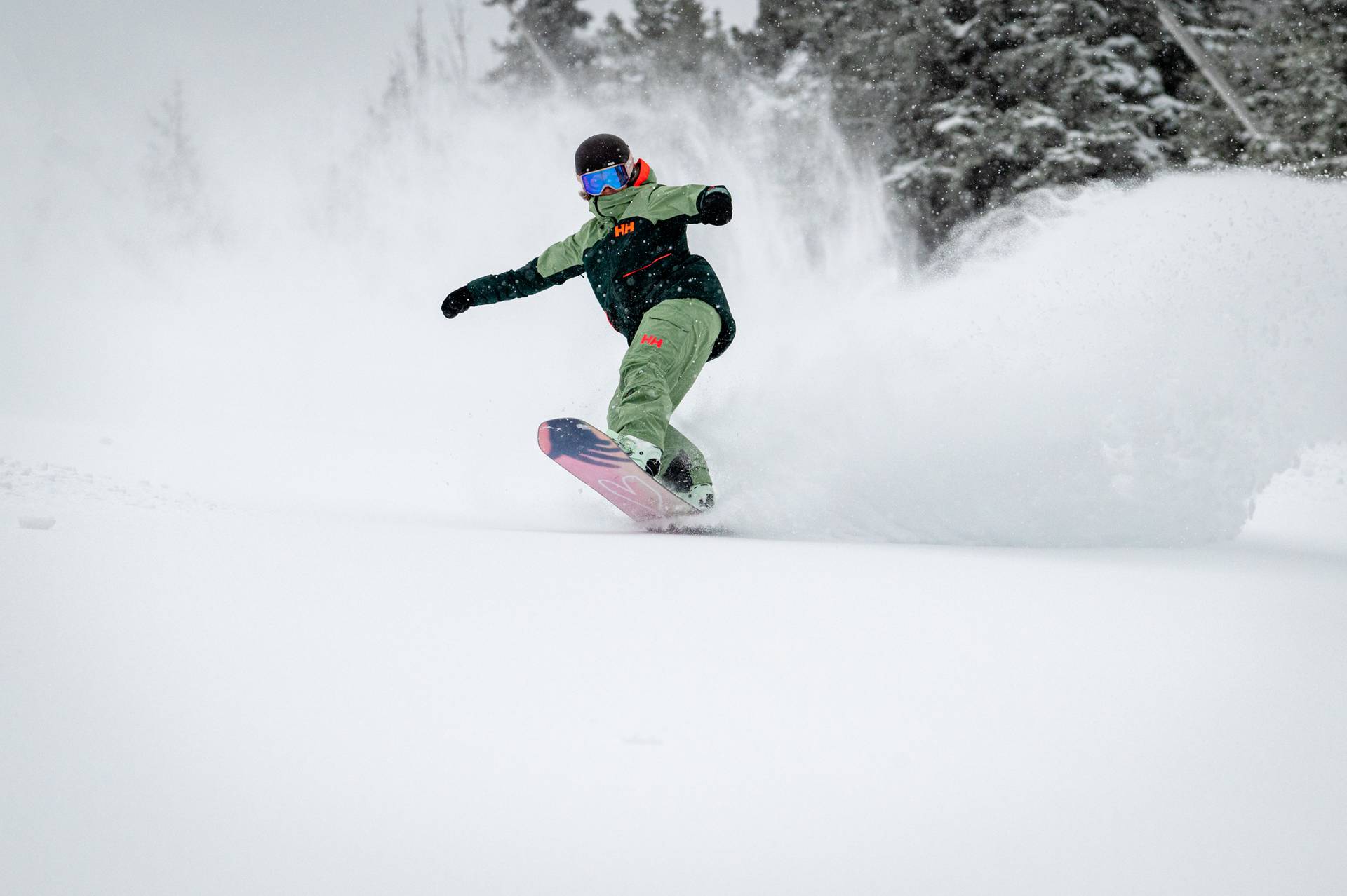 A snowboarder riding through powder in the woods of Sunday River.