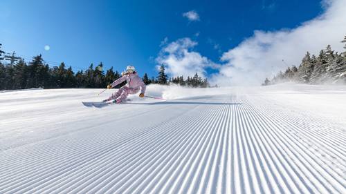 A skier carving turns in fresh corduroy.