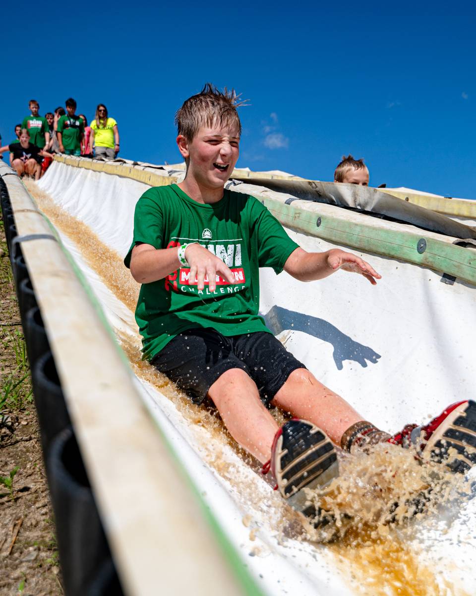 A kid sliding down a water slide at the Mini Mountain Challenge at Sunday River.