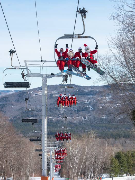Santas on a chairlift at Sunday River for Santa Sunday.
