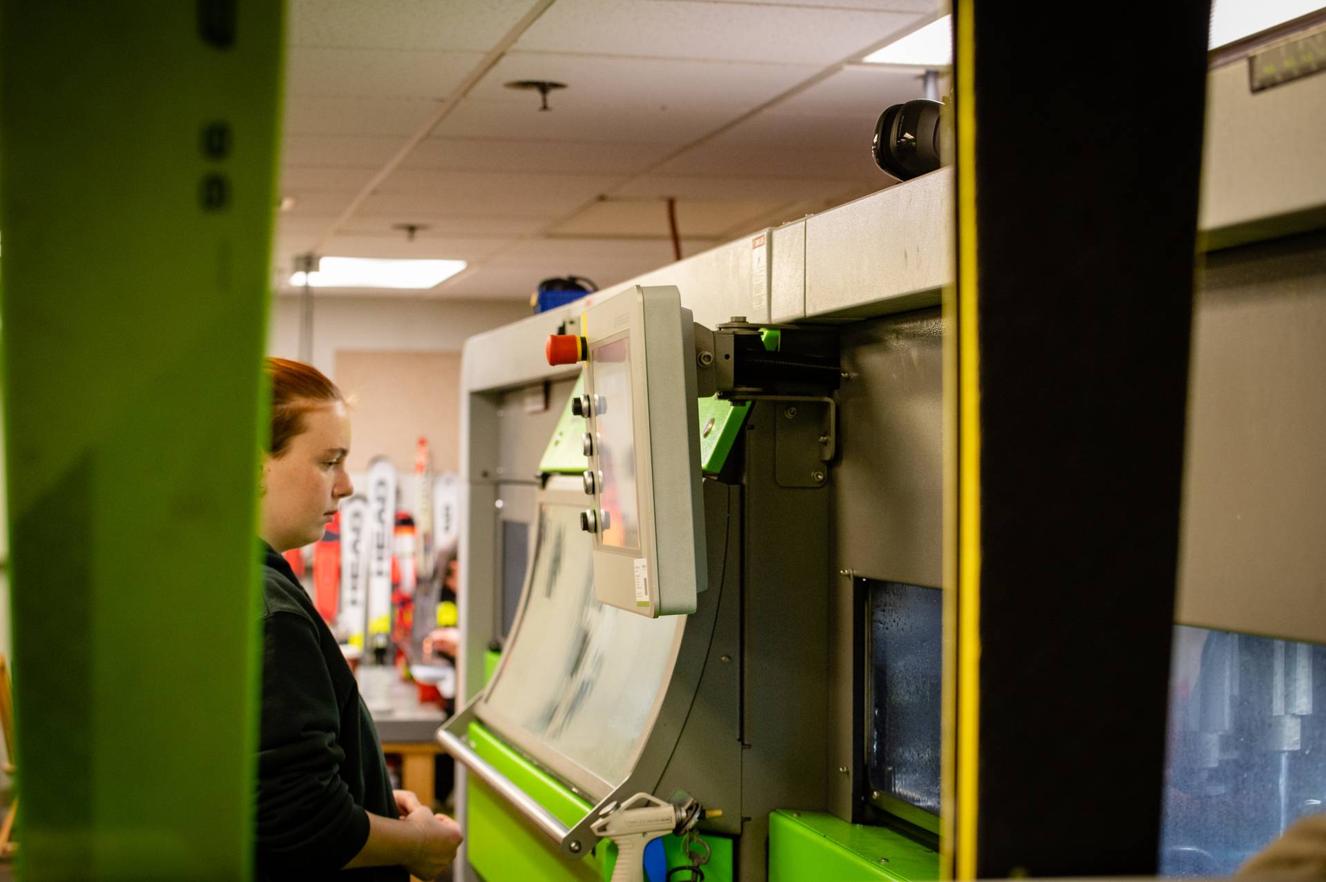 A woman standing in front of a machine while skis are being tuned at Sunday River's Tune Shop.