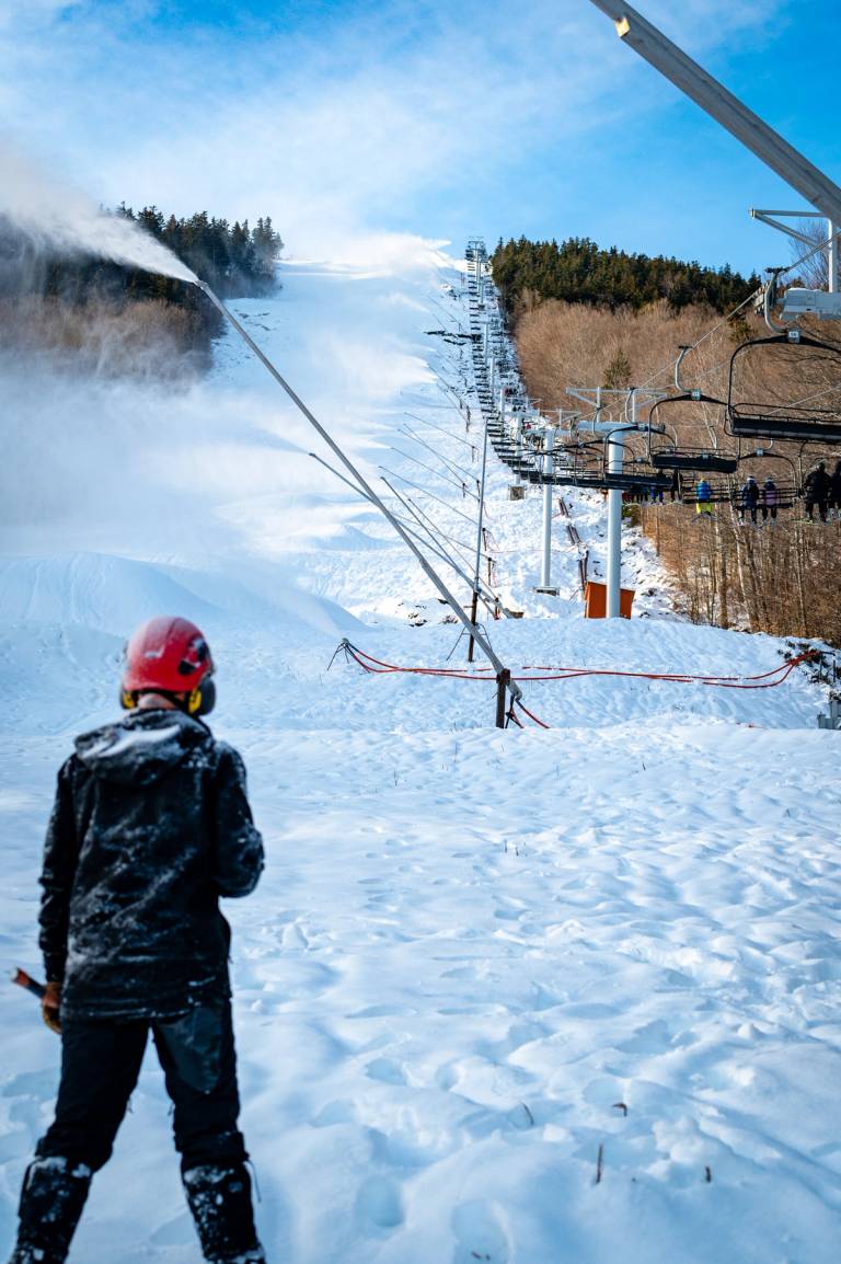 A snowmaker looking at the snowguns lining White Heat, while they are on, at Sunday River.