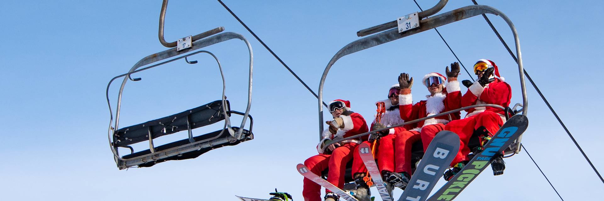 Skiers and riders dressed as Santa sitting on the chairlift at Sunday River.