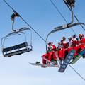 Skiers and riders dressed as Santa sitting on the chairlift at Sunday River.