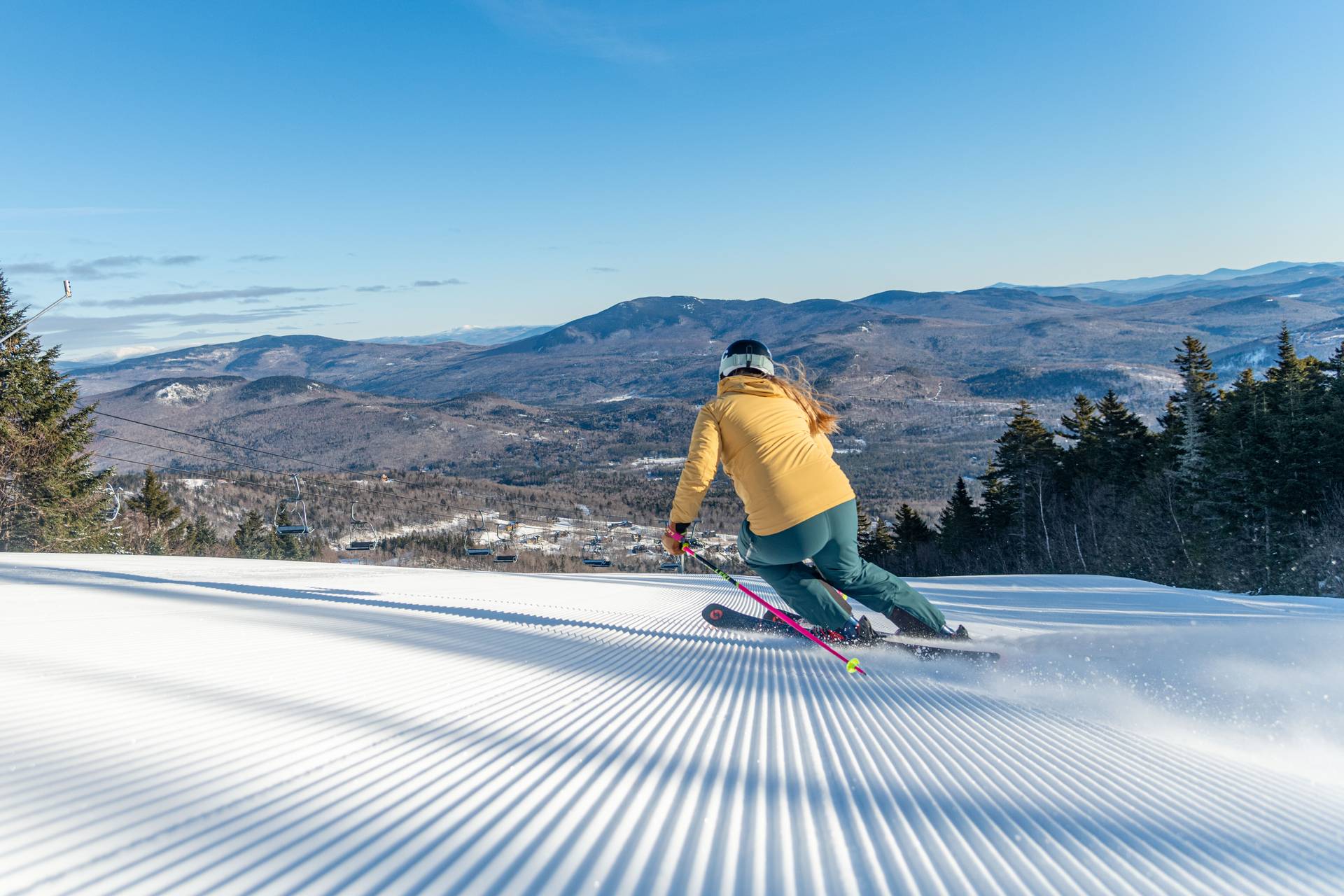 A skier in a yellow jacket skiing at Sunday River.