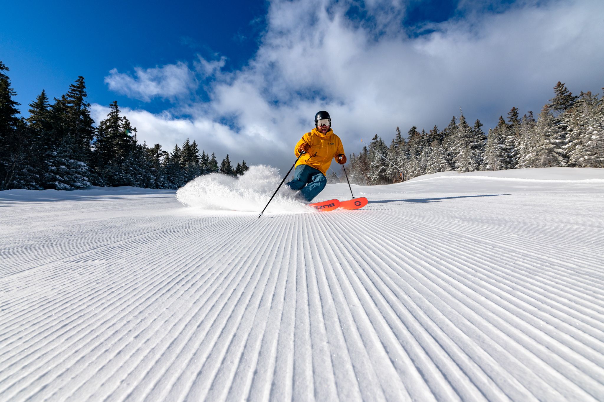 A man skiing down a trail at Sunday River on fresh corduroy. 