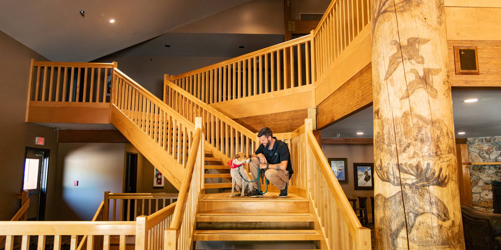 A man and his dog sitting on the steps at the Snow Cap Inn at Sunday River.