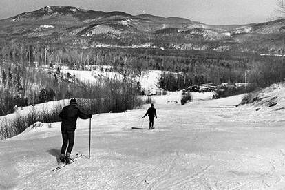 The first skiing at Sunday River in the 1950s. Some skiers going down an ungroomed trail.