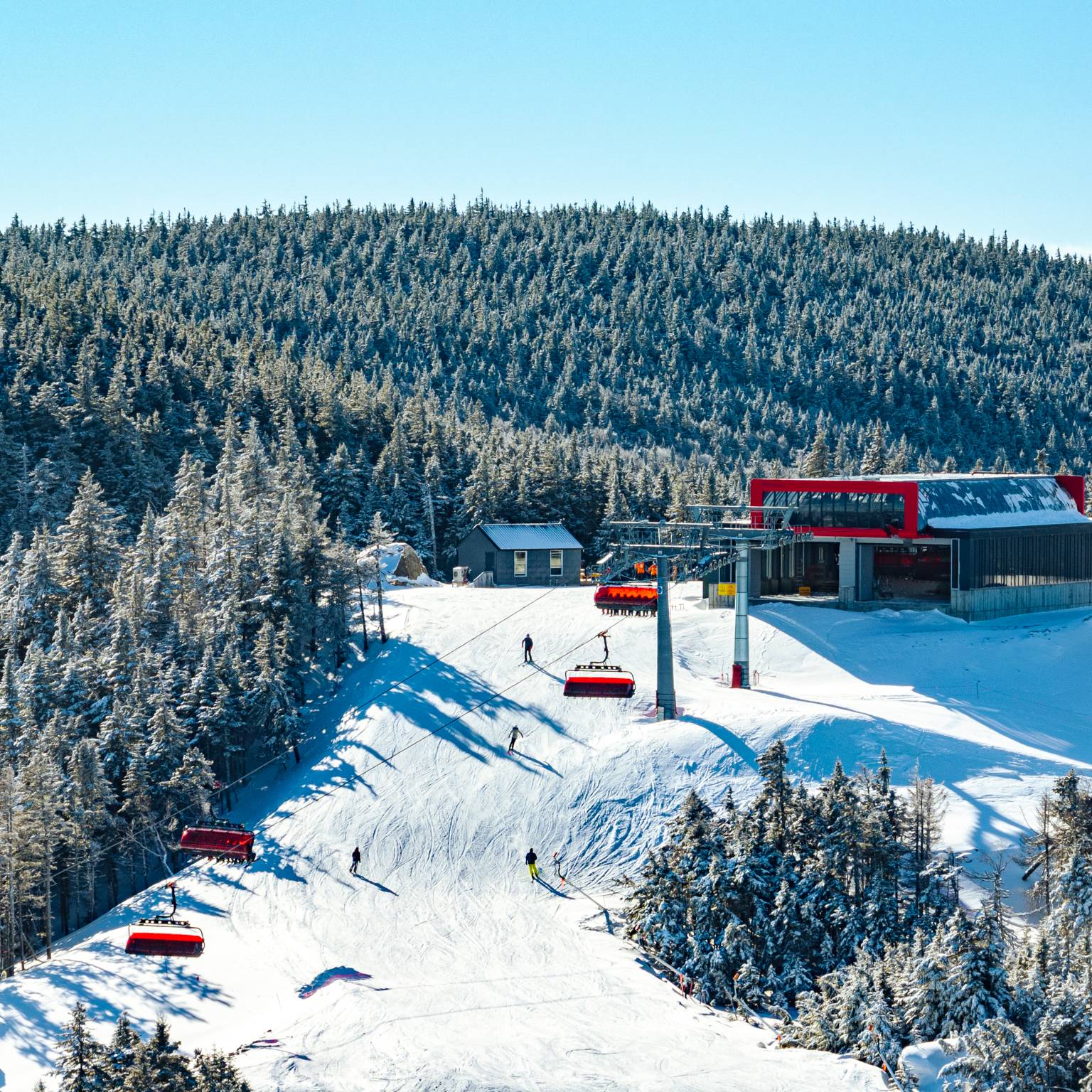 People skiing around, and riding, the Barker 6 lift at Sunday River.