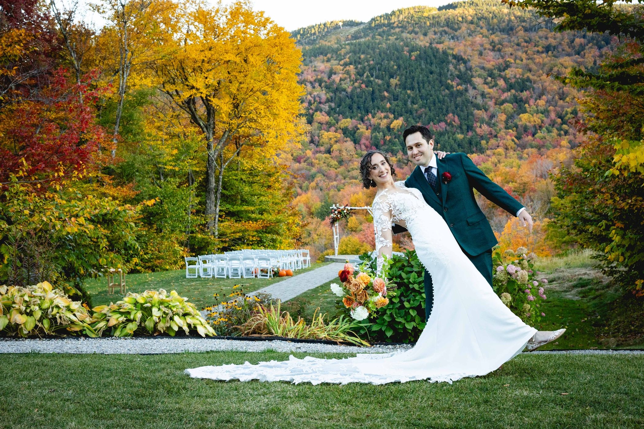 Bride and groom posing with fall foliage in the background.
