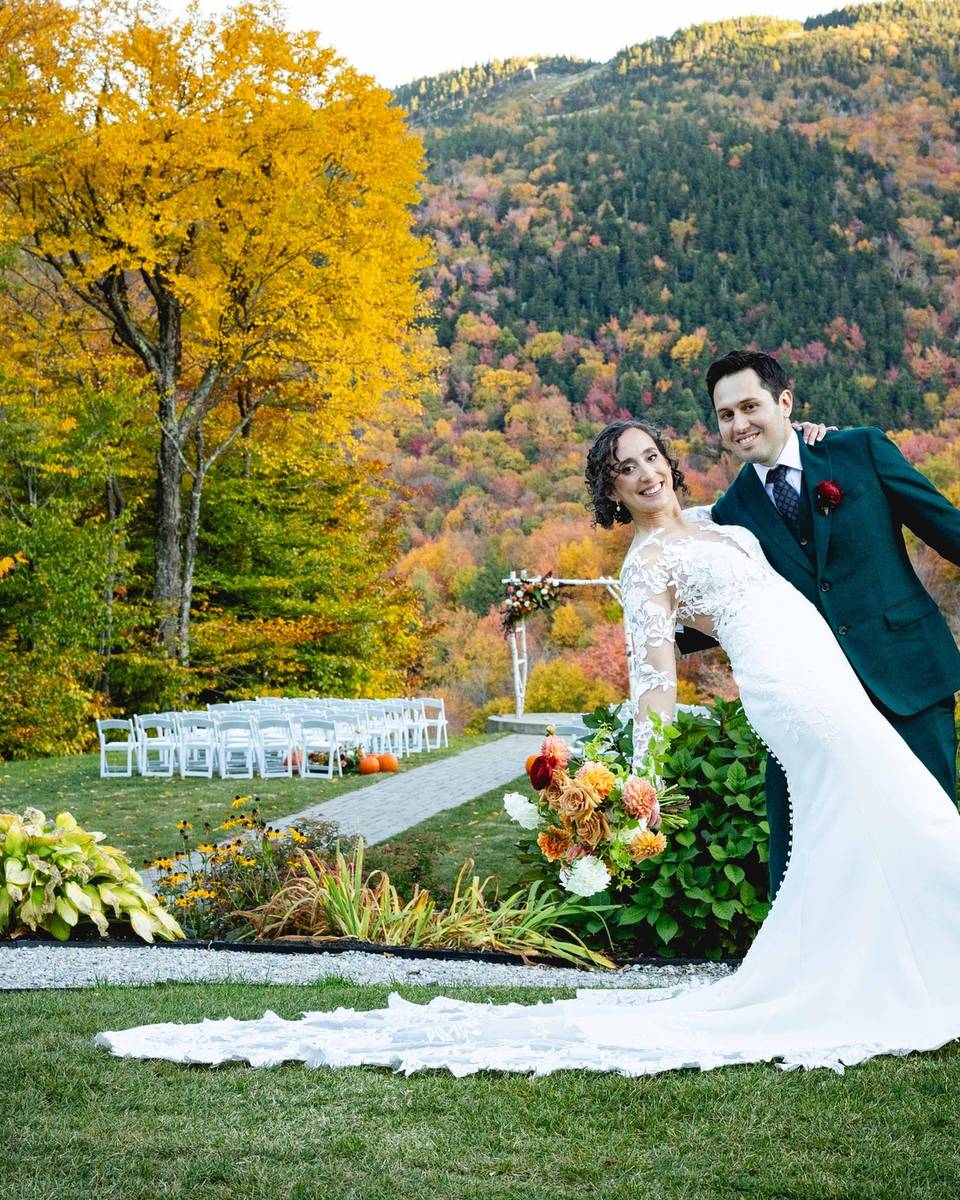 Bride and groom posing with fall foliage in the background.