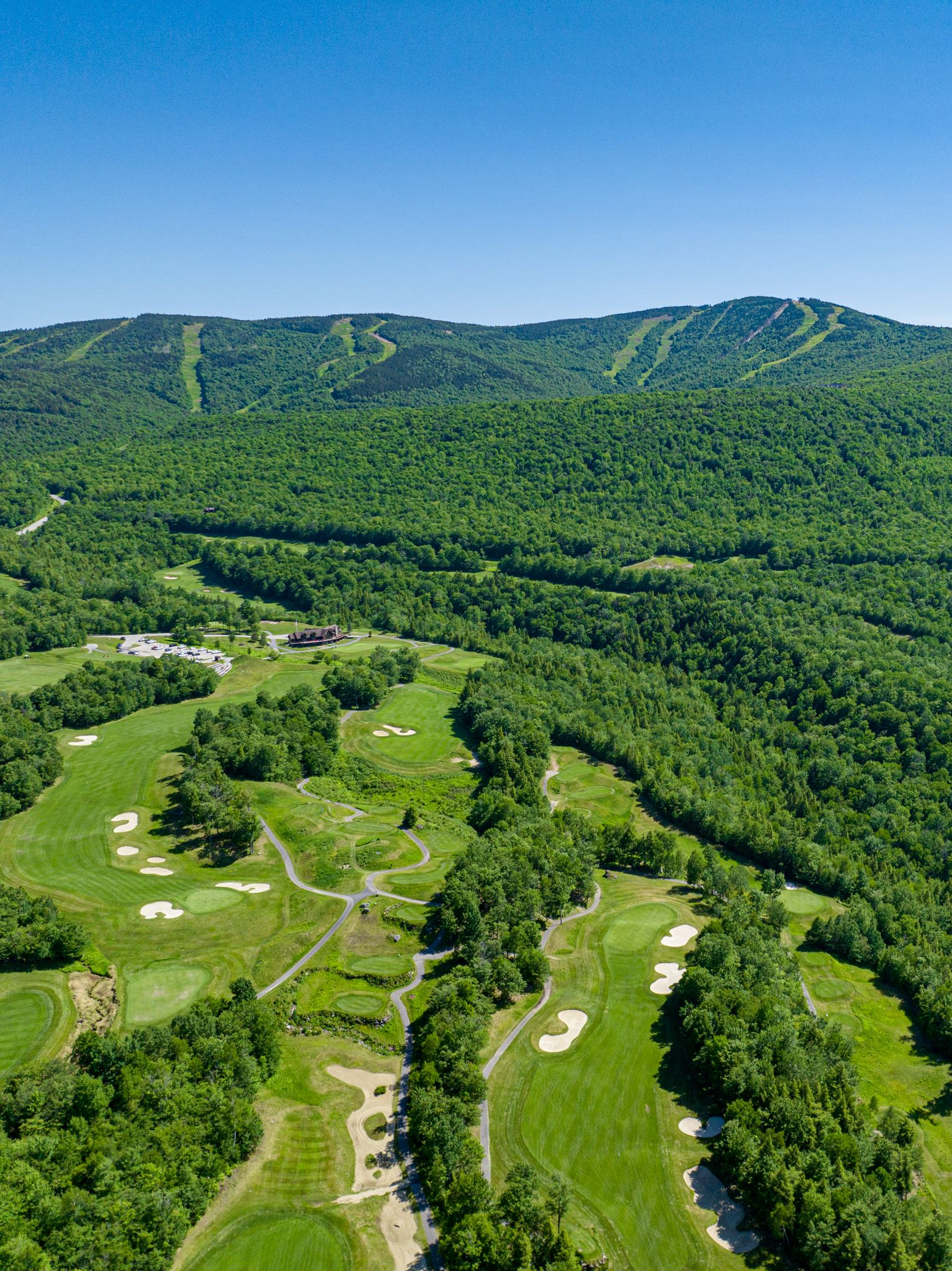 The Sunday River Golf Club in the summer with green trees and greens.