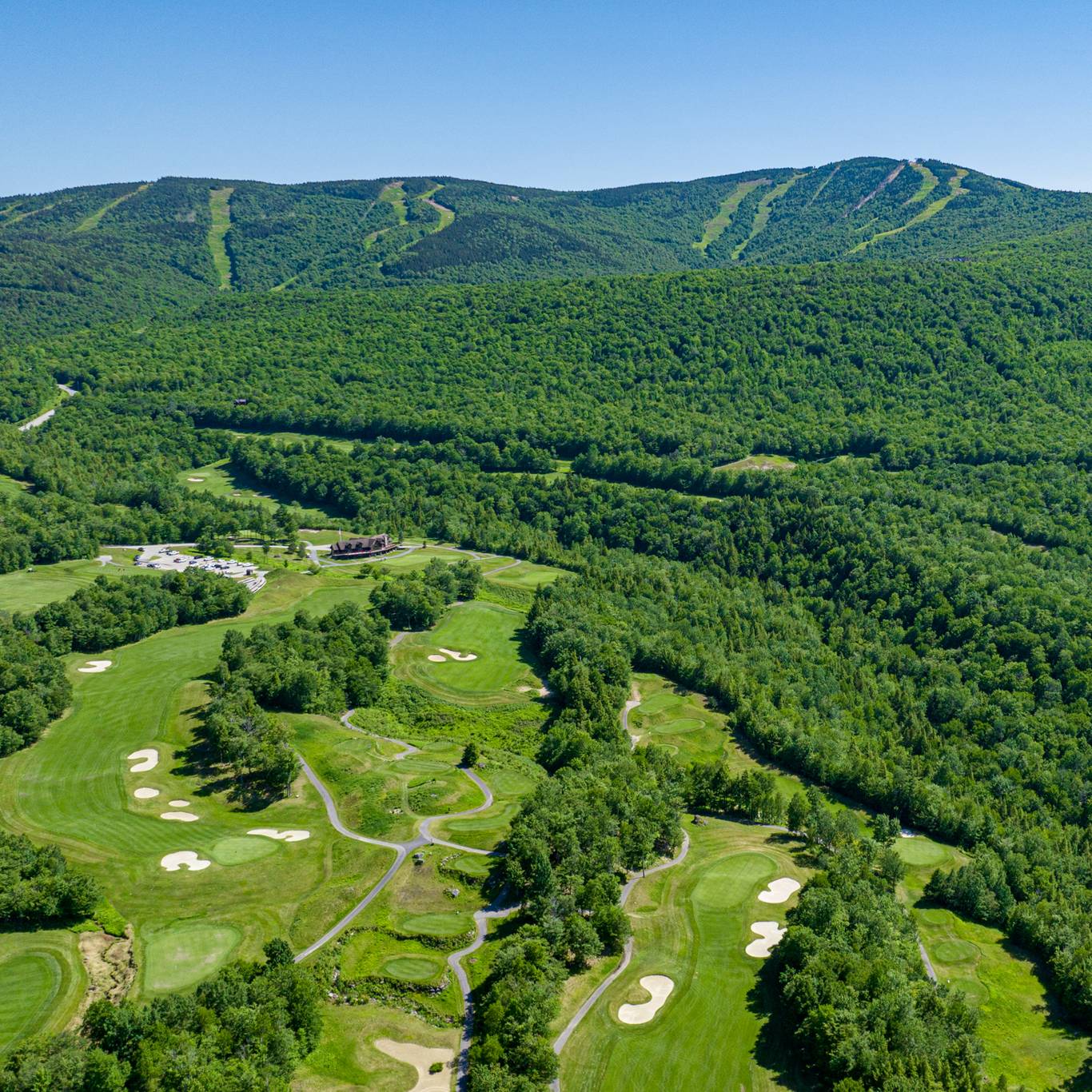 The Sunday River Golf Club in the summer with green trees and greens.