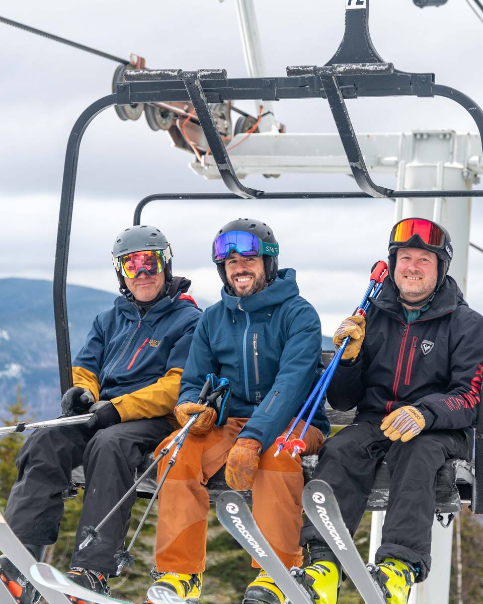People sitting in a chair on a chairlift at Sunday River.