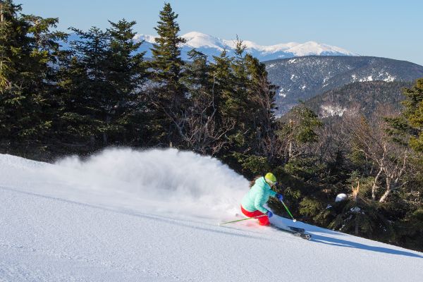 A skier cruising on a trail, with snow trailing behind her, at Sunday River.