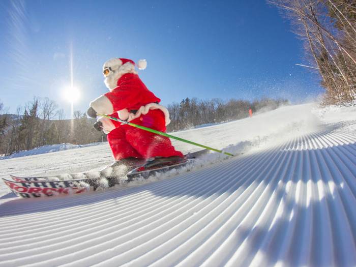 Skier dressed as Santa skiing on corduroy.
