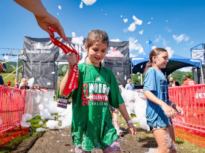 A little girl receiving her medal after finishing the Mini Mountain Challenge at Sunday River.