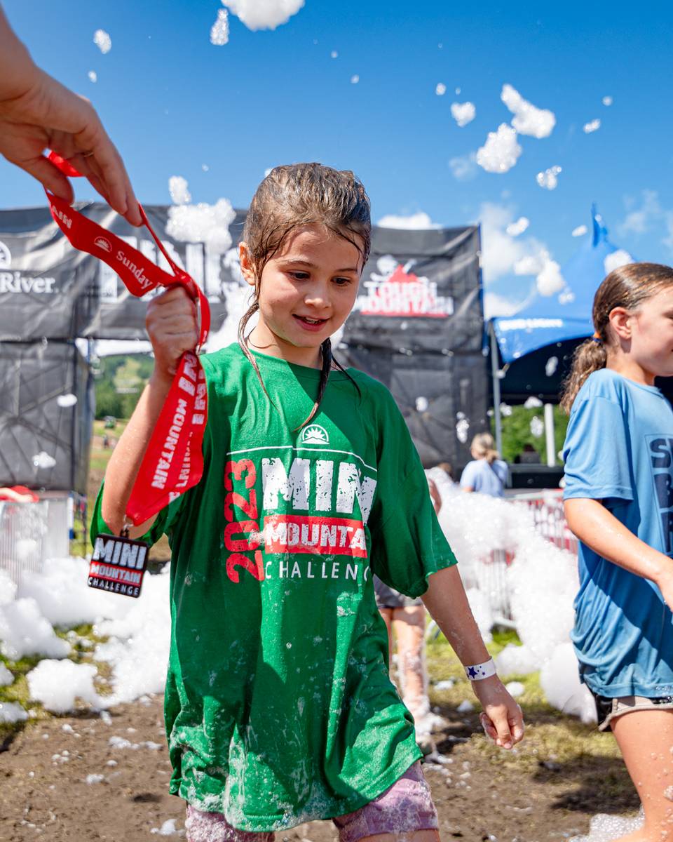 A little girl receiving her medal after finishing the Mini Mountain Challenge at Sunday River.