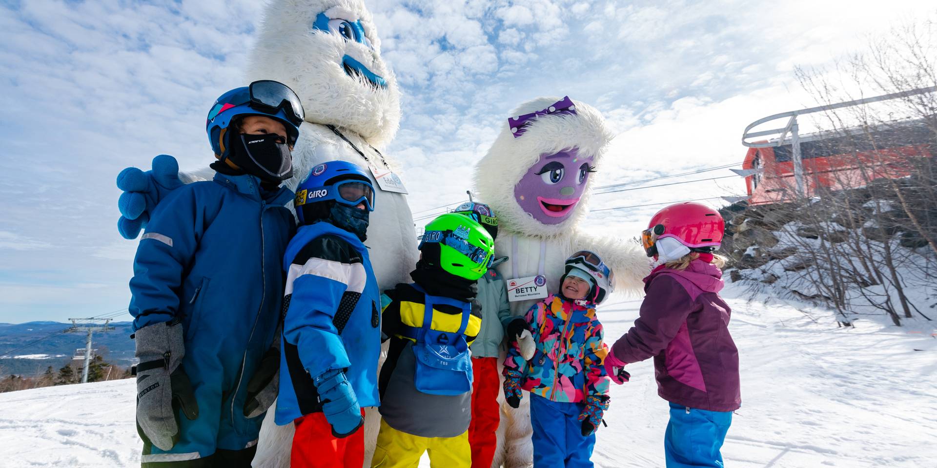 Kids skiing posing with Eddy and Betty the Yetis at Sunday River.