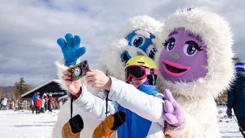 Eddy and Betty the Yetis posing for a picture with a young kid.