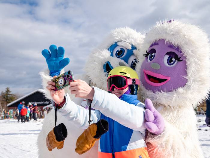 Kid posing for a picture with Eddy and Betty the Yetis.