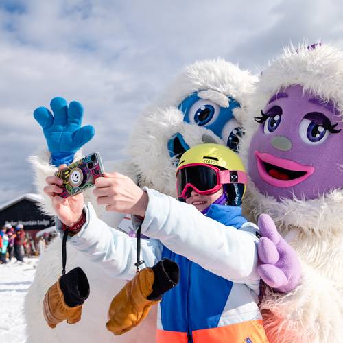Eddy and Betty the Yetis taking a photo with a young kid.