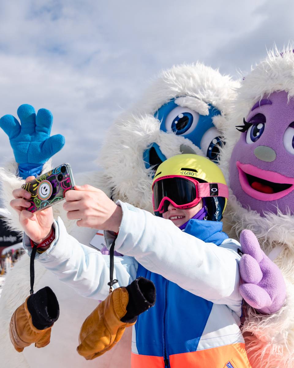 Kid posing for a picture with Eddy and Betty the Yetis.