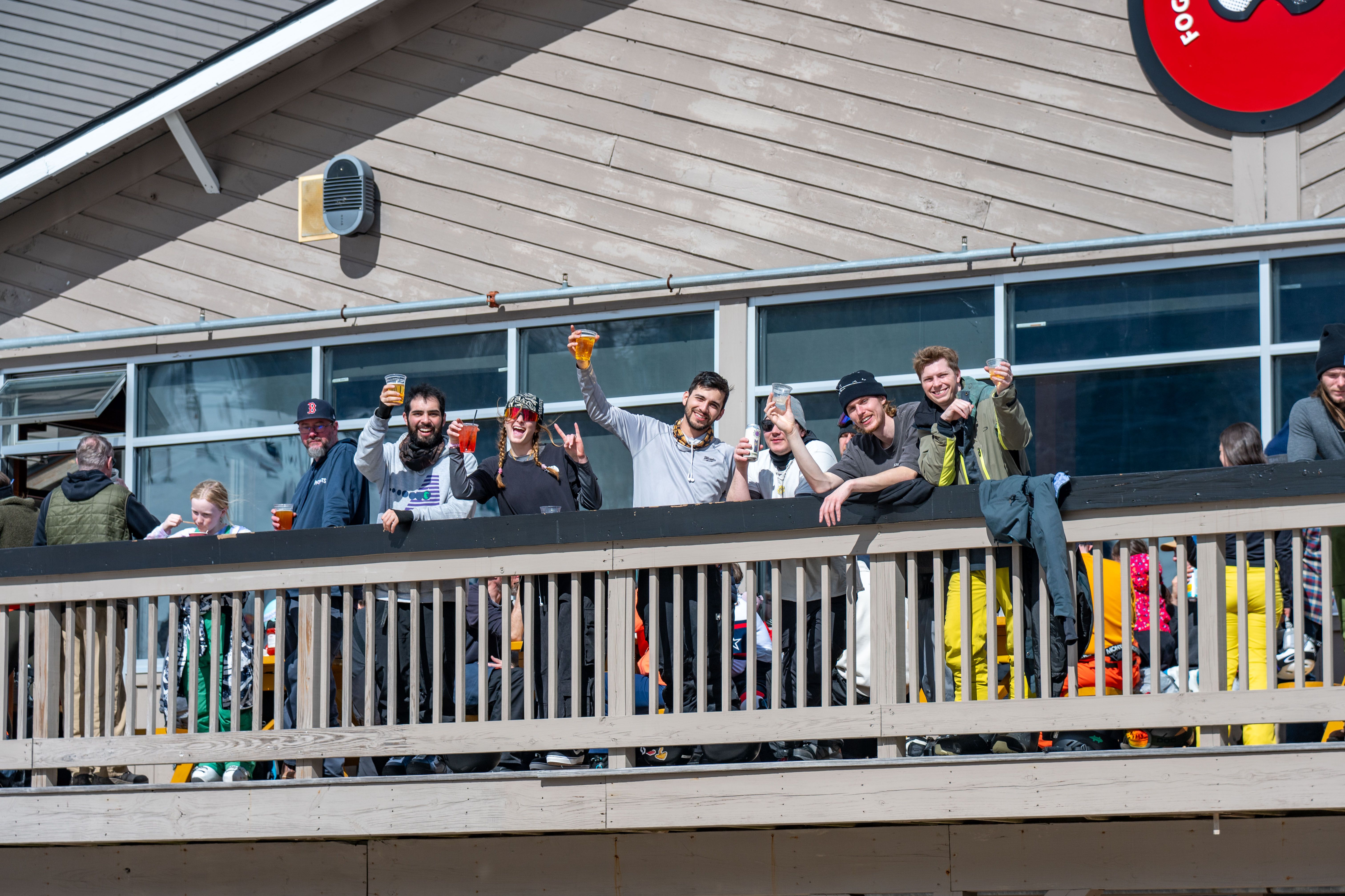 People posing for a photo with their drinks on the Foggy Goggle deck at Sunday River.