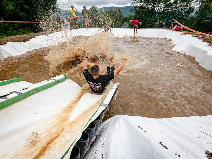 A runner in Tough Mountain Challenge sliding down a waterslide.