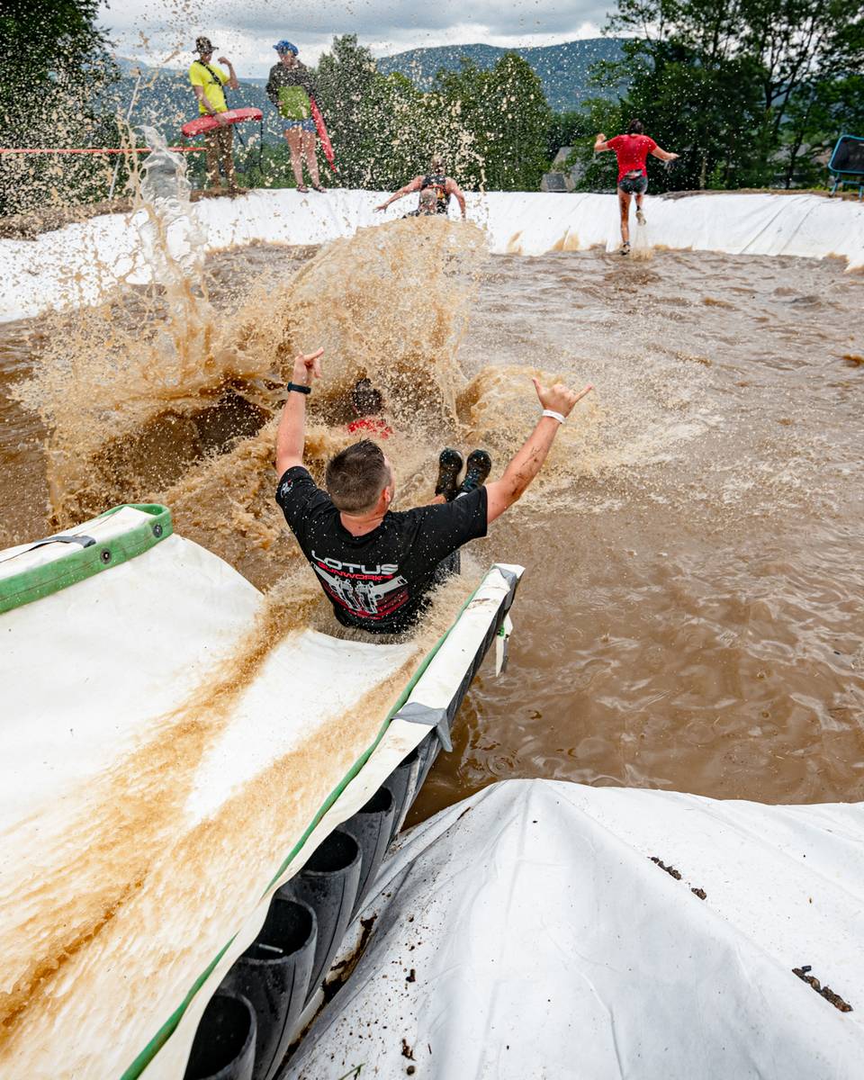 A runner in Tough Mountain Challenge sliding down a waterslide.