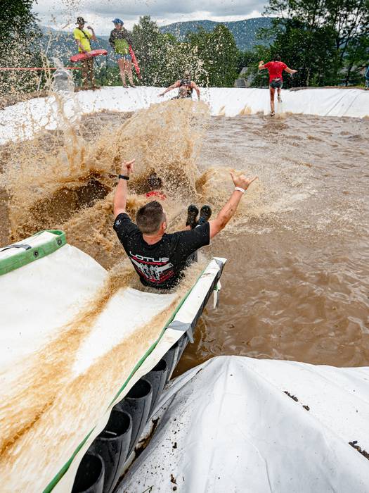 A runner in Tough Mountain Challenge sliding down a waterslide.