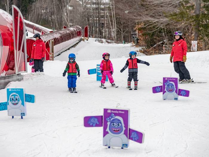 Kids taking a lesson by the magic carpets at Sunday River.