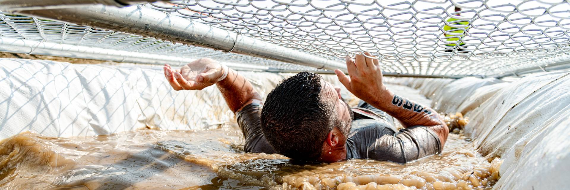 A competitor at Tough Mountain Challenge going through a mud obstacle.