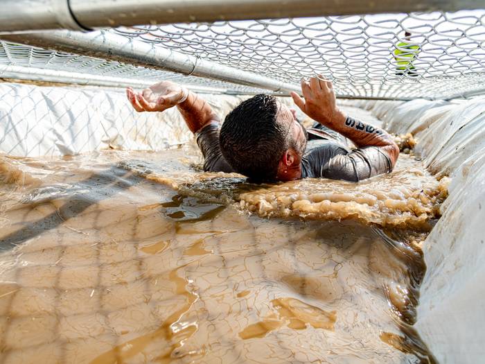 Man going through a mud obstacle at Sunday River's Tough Mountain Challenge.