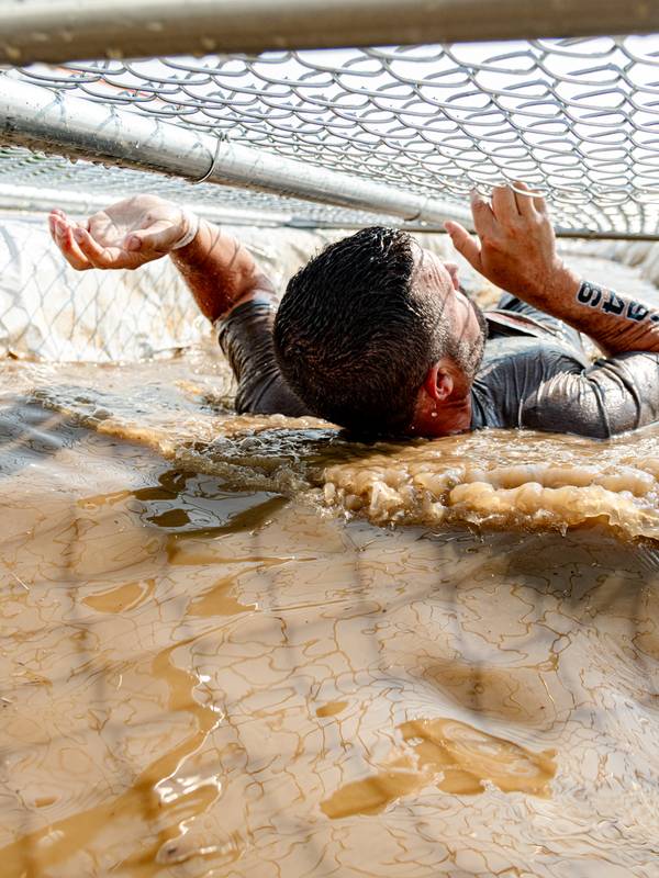 Man going through a mud obstacle at Sunday River's Tough Mountain Challenge.