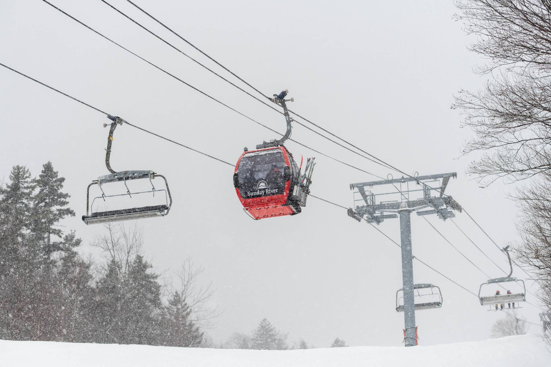 Snow falling down on the chondola cabins at Sunday River.