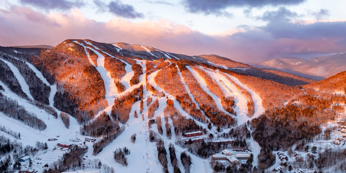 The sun rising over the peaks at Sunday River in the winter time.