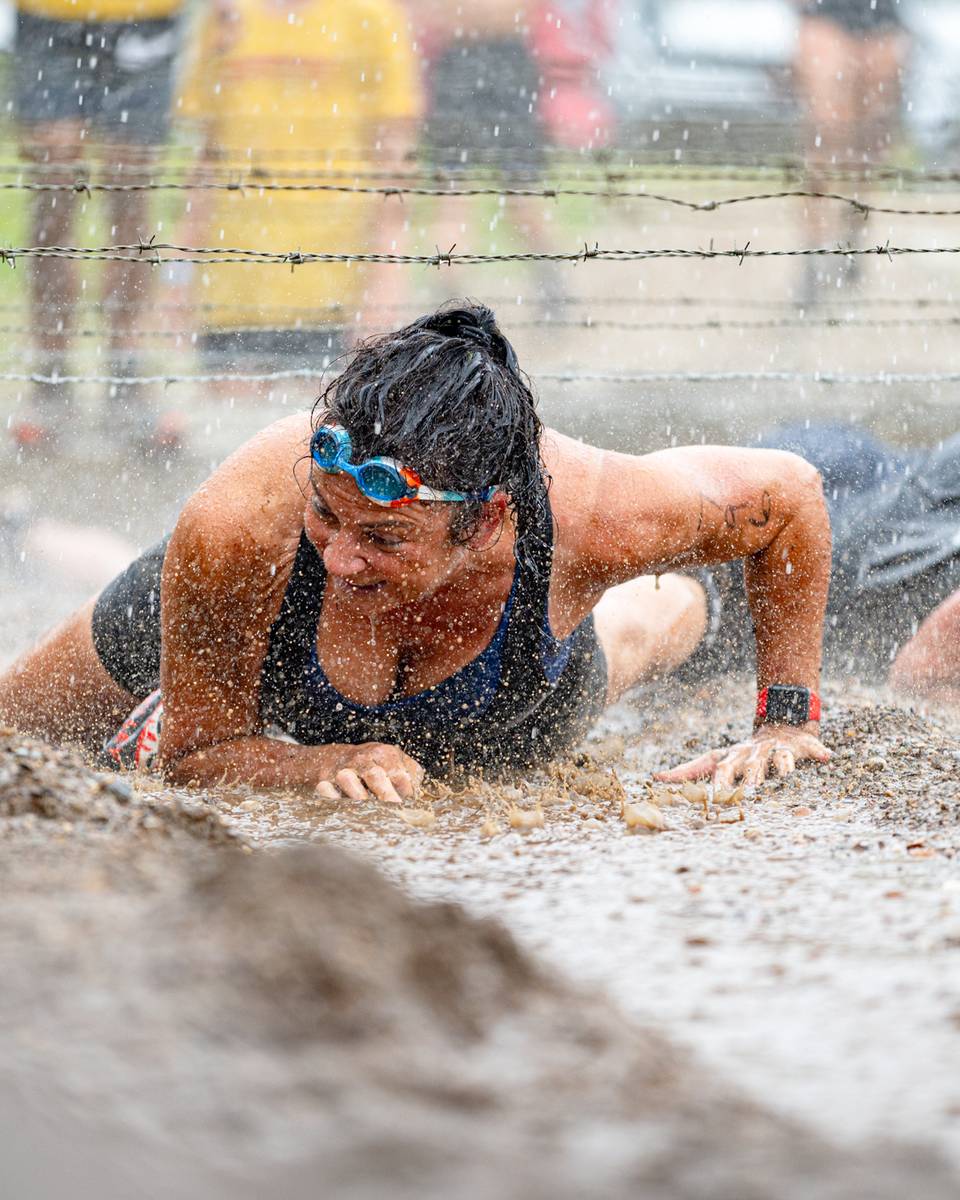 A woman crawling under barbed wire at the Tough Mountain Challenge.
