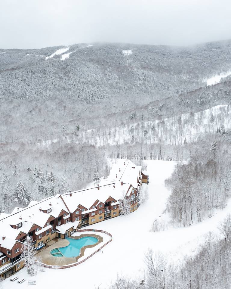 The exterior of the Jordan Hotel at Sunday River with snow on the trails and around the pool.