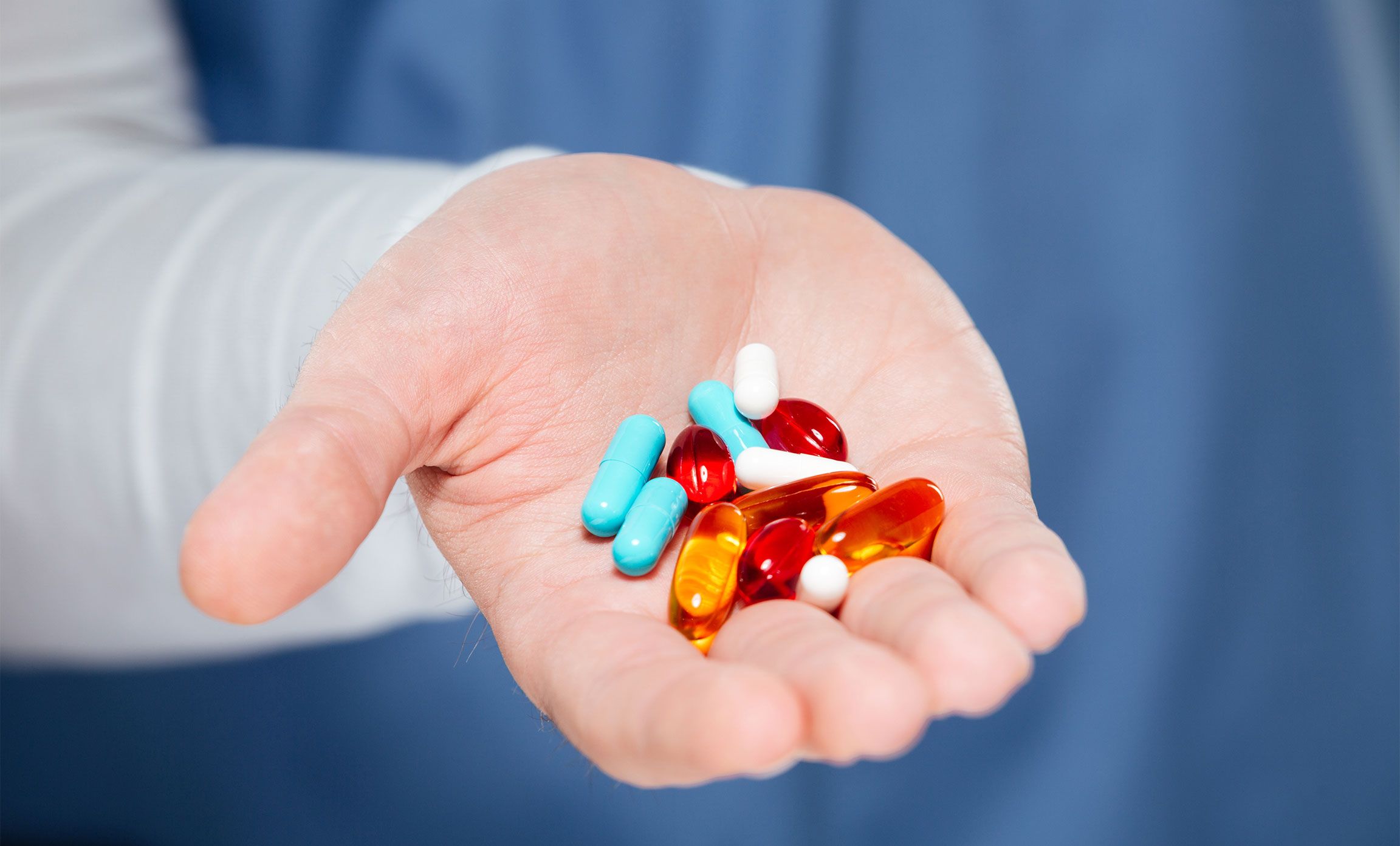 Hand holding capsules and tablets, symbol of antibiotic use.
