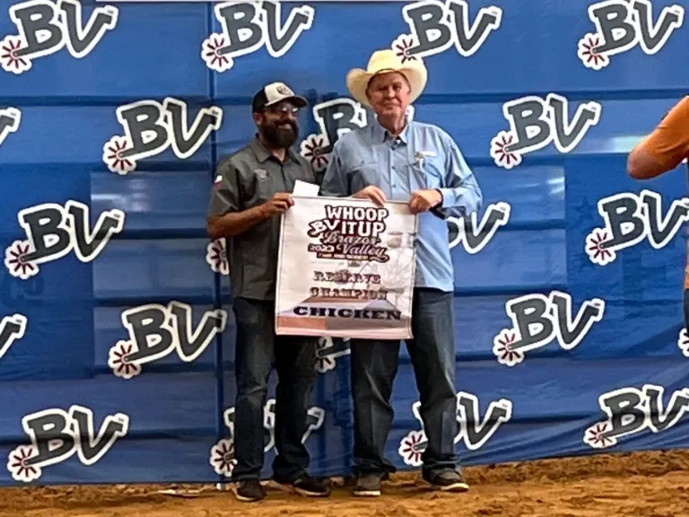 Two men pose with a printed apron in front of a blue BV backdrop.