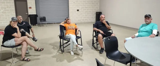 Guests relax in folding chairs along the wall of the event hall.