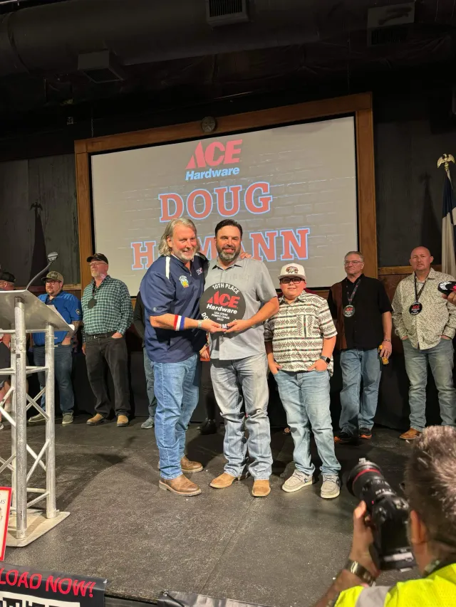 Two men and a child pose together during an onstage awards presentation.