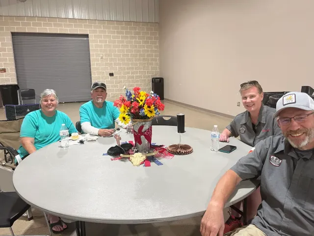 Four guests smile from a round table in the event hall.