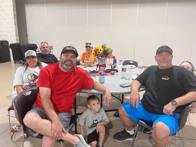 Adults and a young child gather around a table in the event hall.