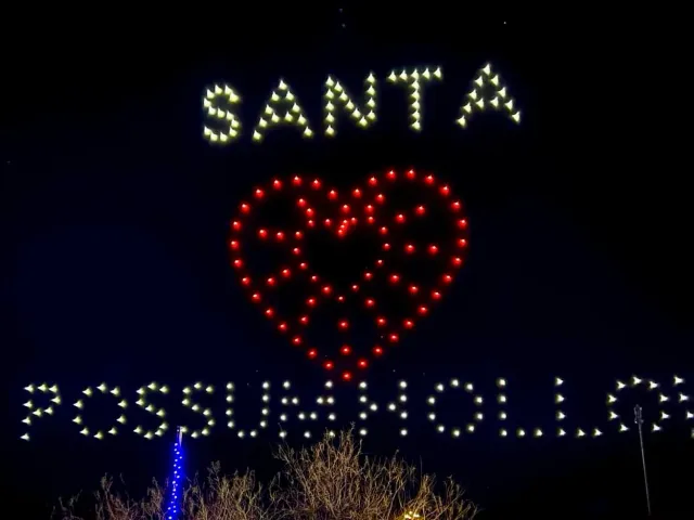 A nighttime light display spells Santa above a red heart and illuminated lettering.