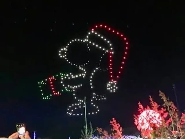 A nighttime light display outlines a smiling face in a red Santa hat.