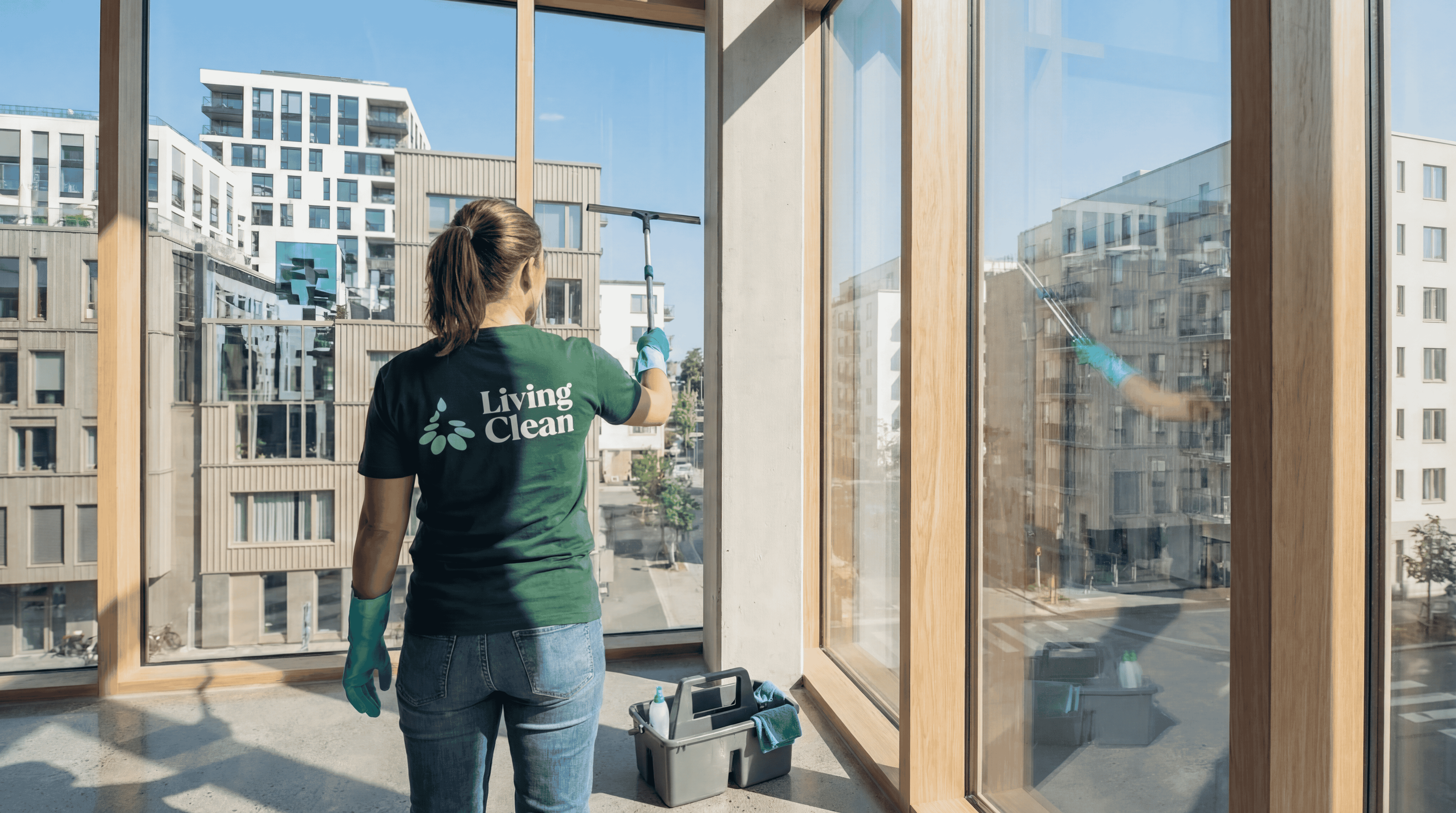 Living Clean-ansatt vasker store vinduer i en bygård med gateutsikt.