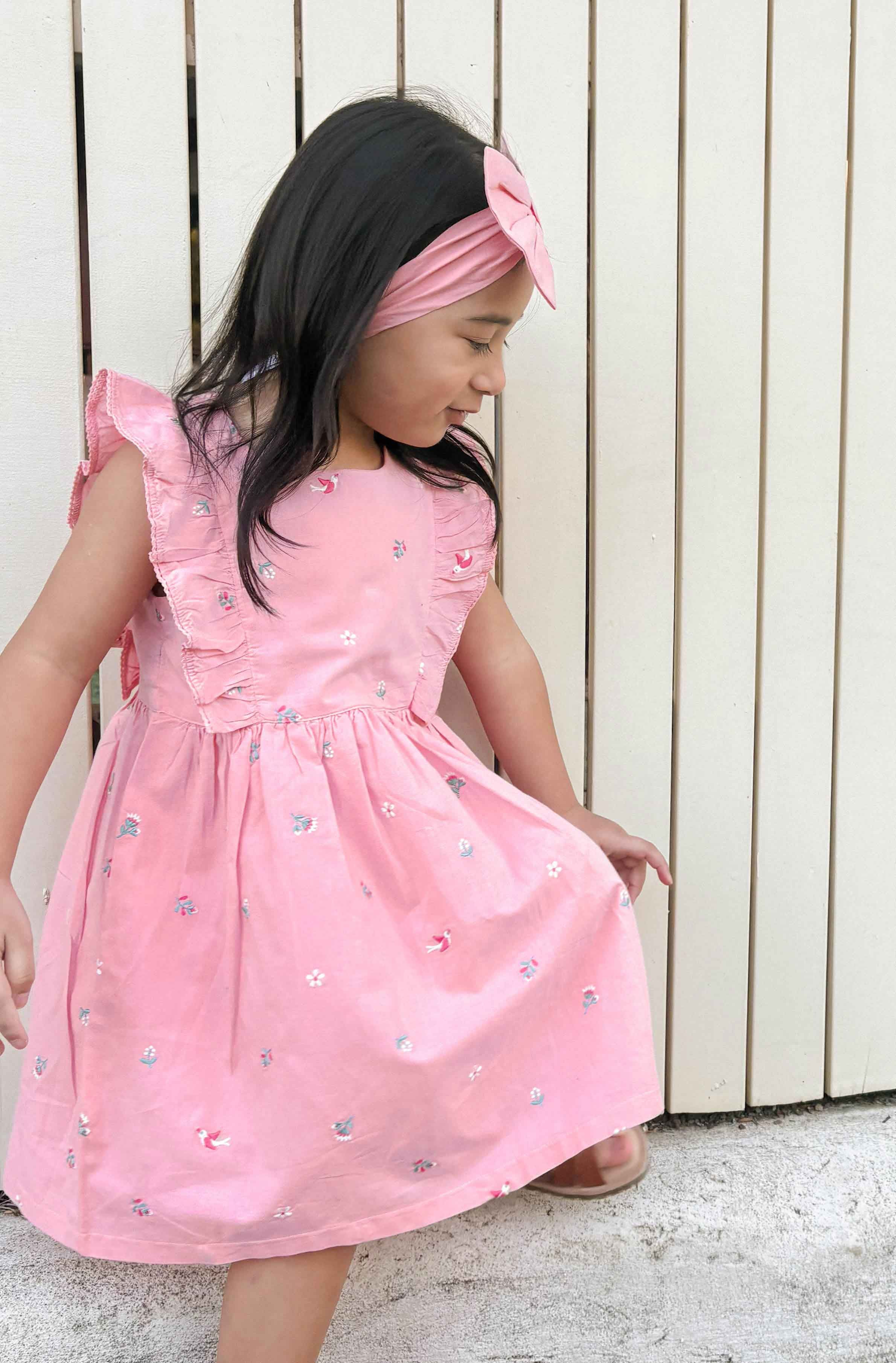Girl in a pink sleeveless cotton summer dress enjoying a sunny day